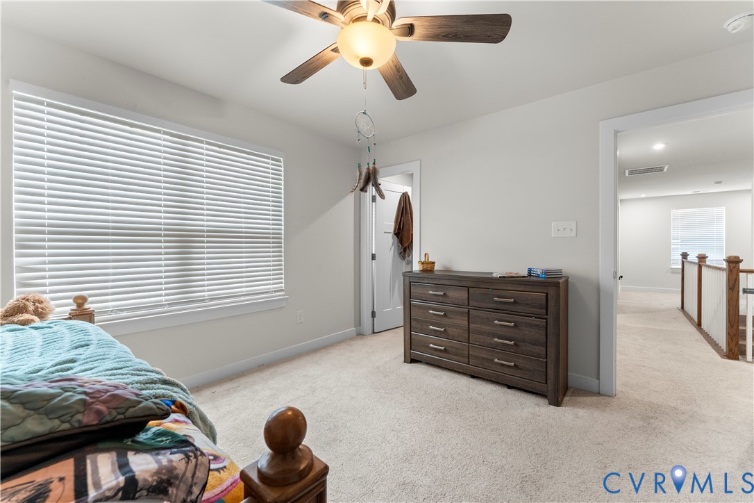 Carpeted flooring, ceiling fan with light fixture, window with blinds, and white walls