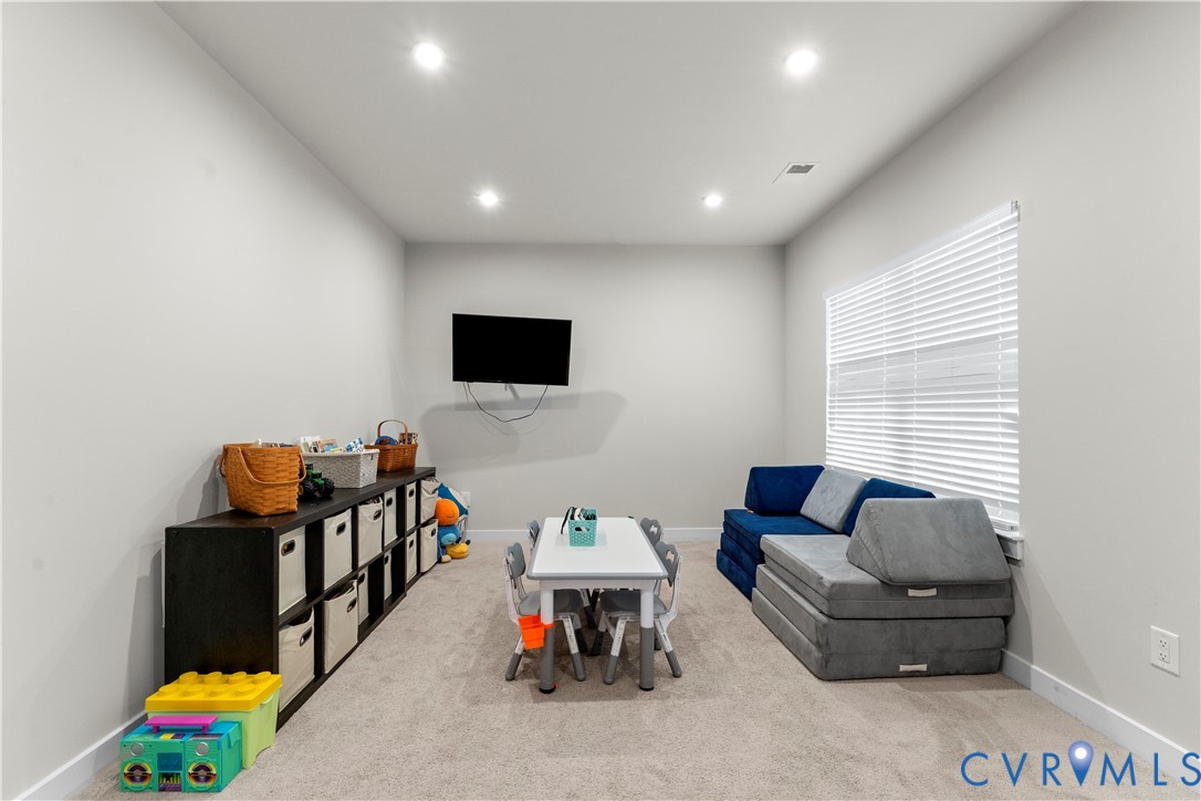 Recessed lighting, wall-mounted television, window with horizontal blinds, and neutral-toned wall paint