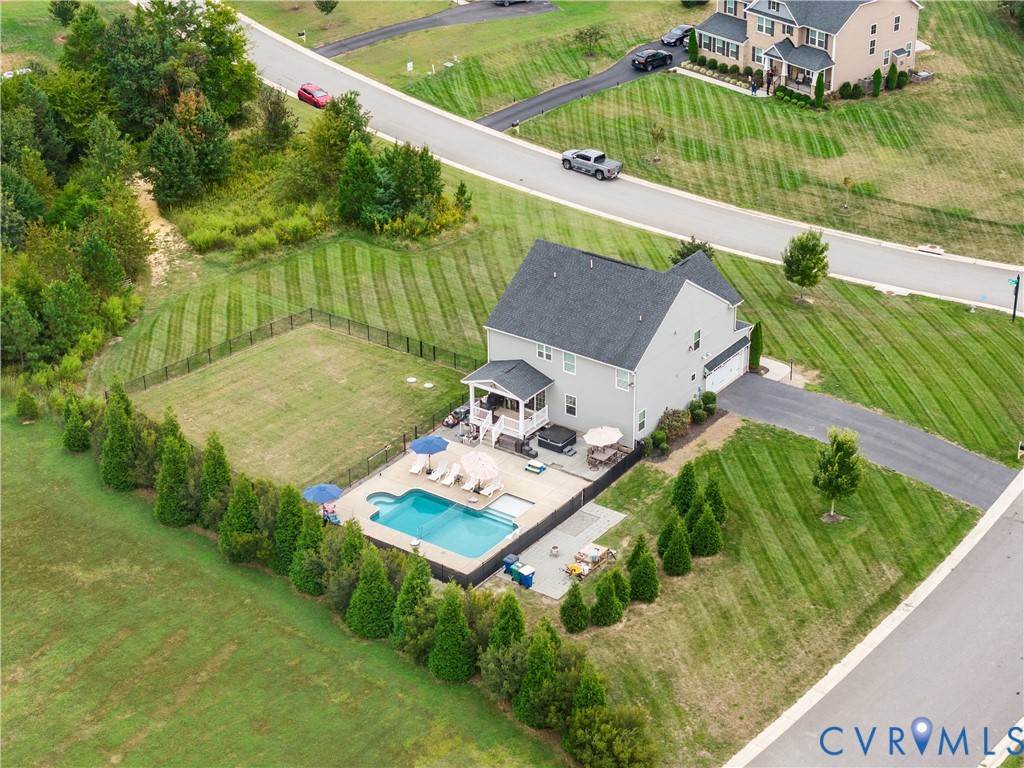In-ground swimming pool, expansive paved patio, covered porch, attached two-car garage, and fenced yard