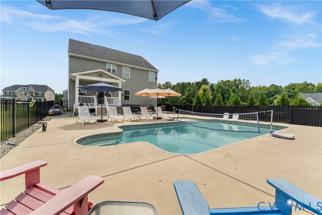 Two-story residence with a patio, in-ground swimming pool, and black metal fencing