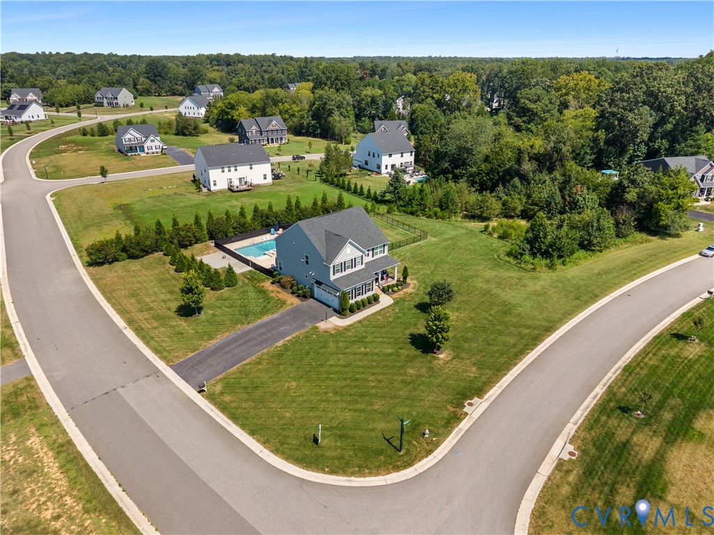 Residential property with a corner lot, private swimming pool, paved driveway, and mature landscaping