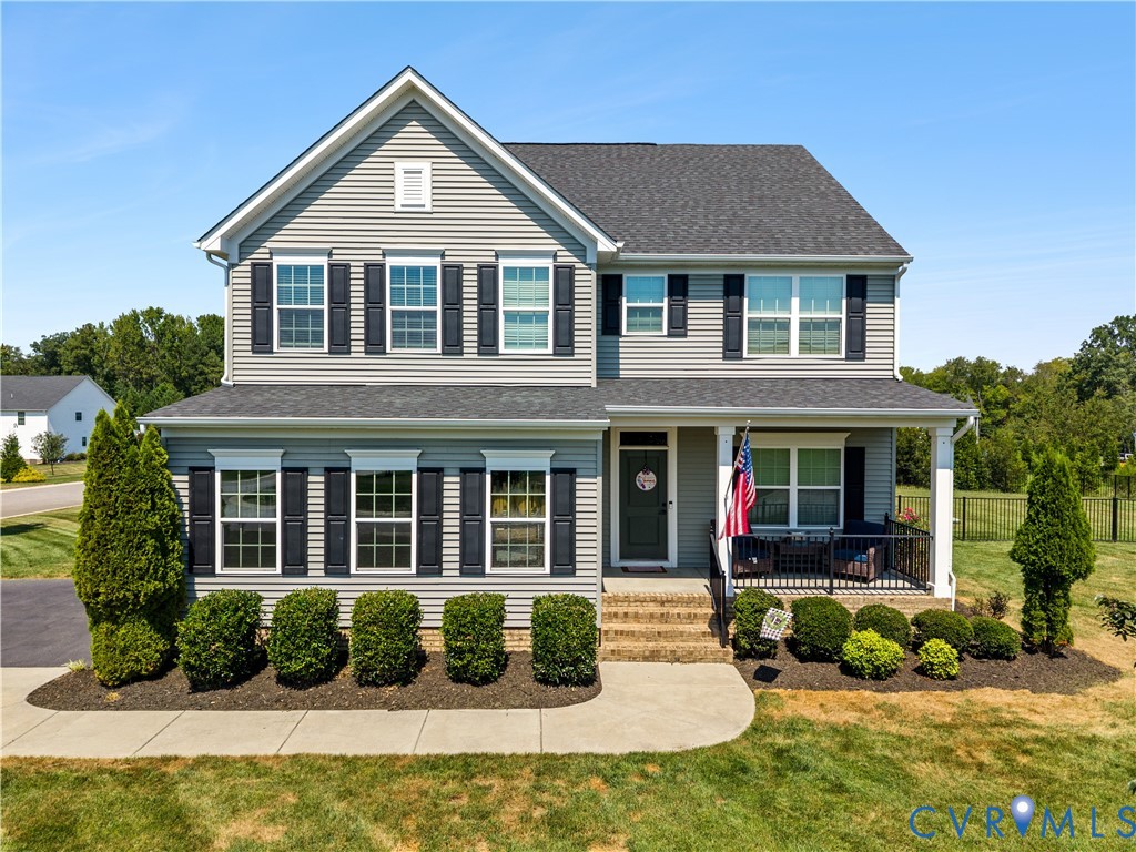 Two-story home with a covered front porch, gray siding, black shutters, and a dark shingle roof