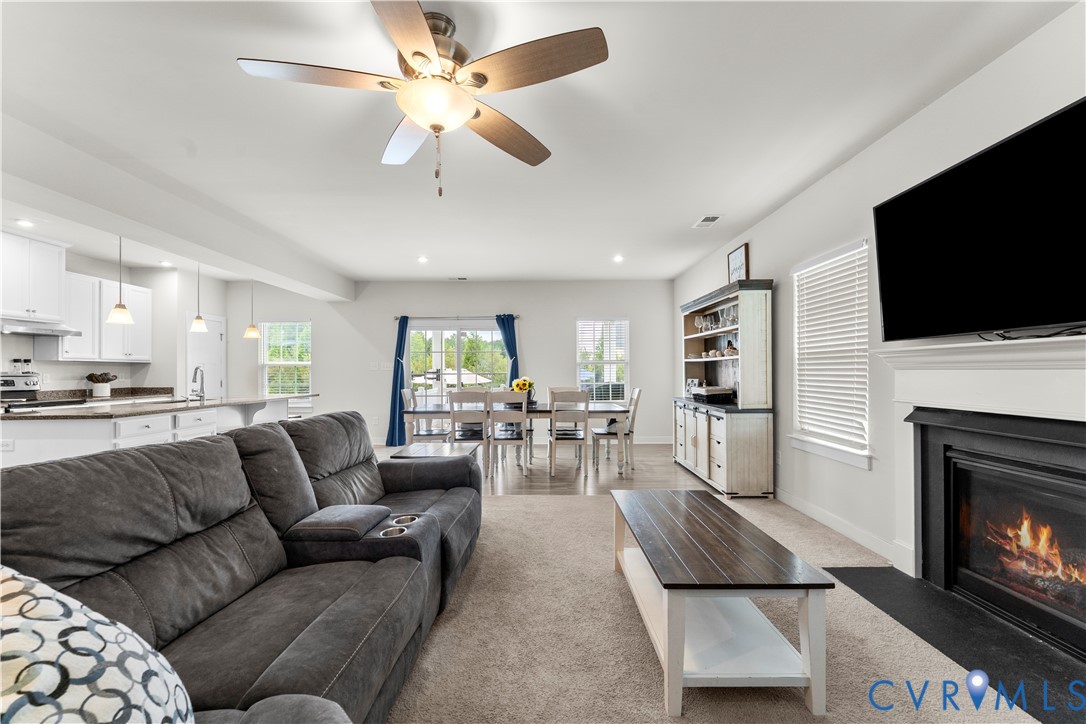 Open-concept living area featuring a ceiling fan, fireplace with mantel, and recessed lighting