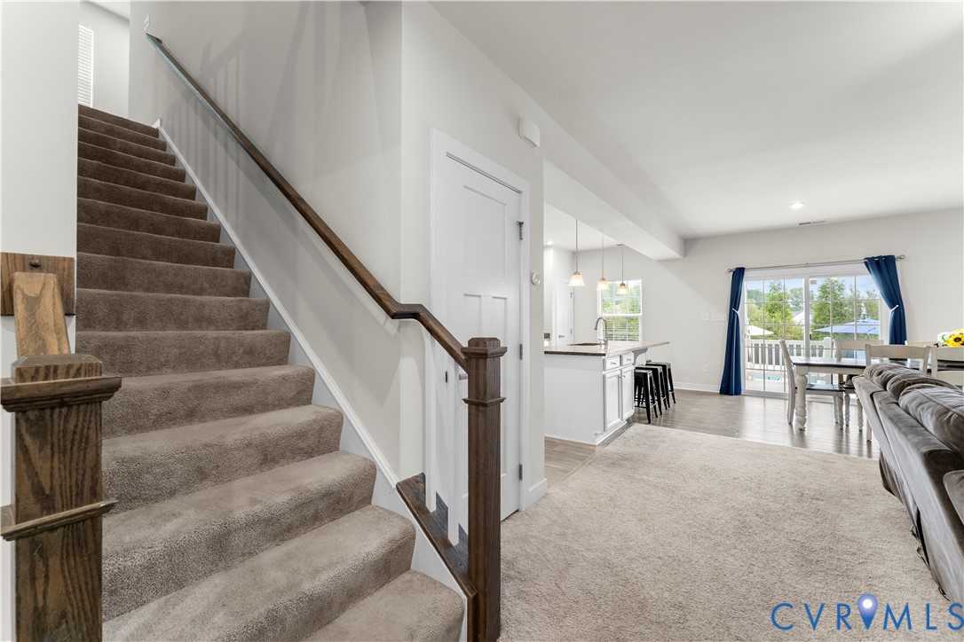 Carpeted staircase with wood-finish handrail and newel post