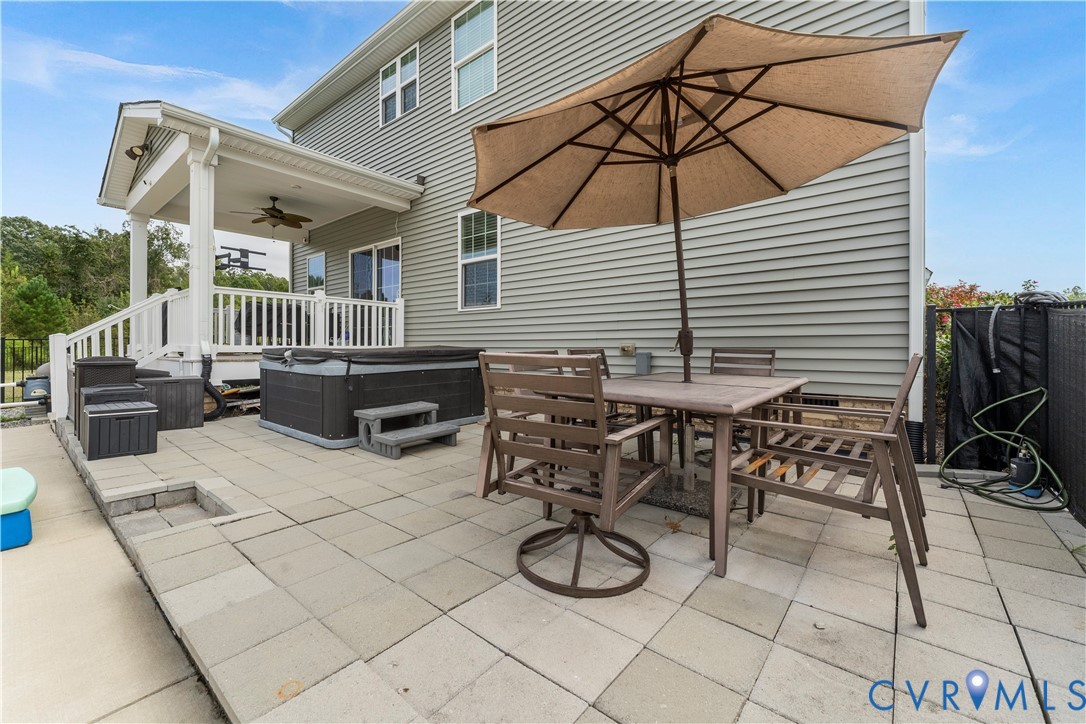 Expansive paver patio with covered porch, hot tub, and exterior siding