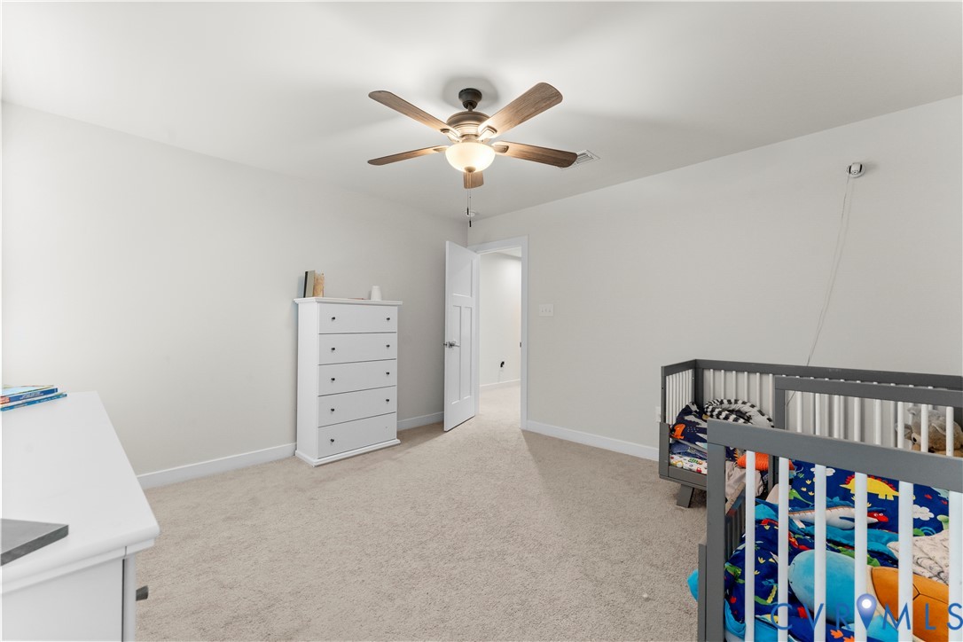 Plush carpet flooring, neutral wall tones, and a ceiling fan with integrated lighting