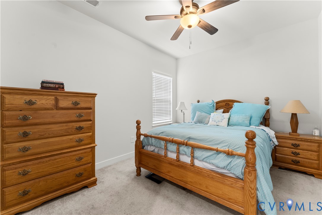 White walls with a ceiling fan light fixture, wood-finish flooring, and a window with blinds