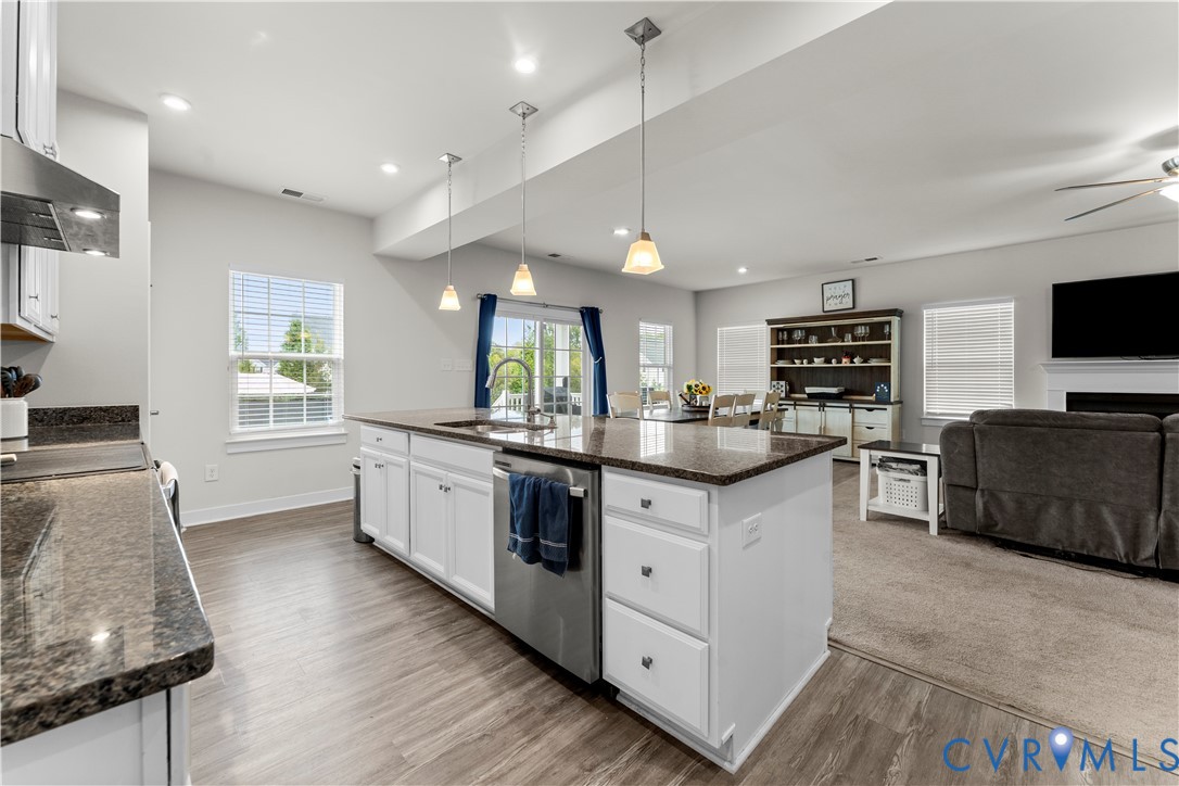 Open-concept kitchen featuring an island with built-in sink, white cabinetry, and dark countertops