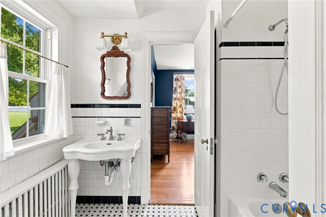 White subway tile, pedestal sink, mosaic tile flooring, and a shower/tub combination