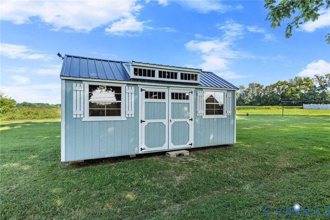 She Shed/Storage building featuring horizontal siding, double entry doors, multiple windows, and decorative shutters