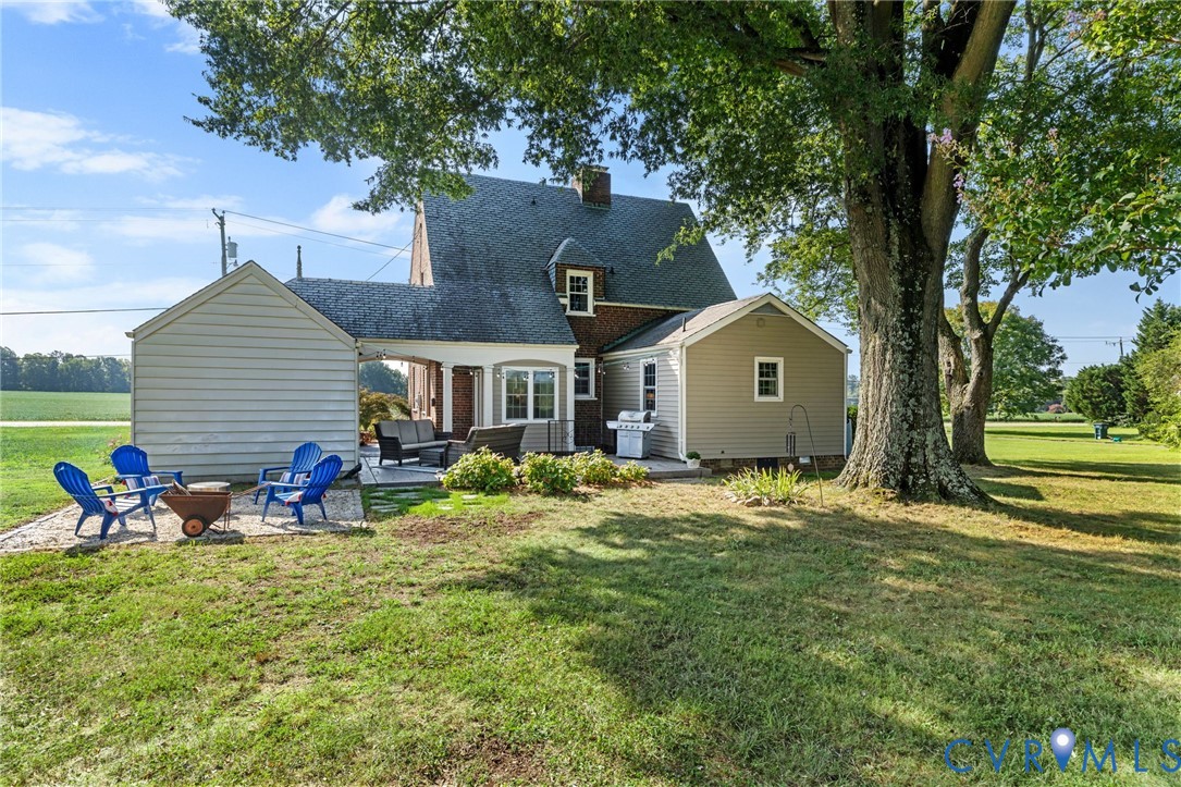 Expansive backyard featuring a manicured lawn, established shade trees, and a stone patio