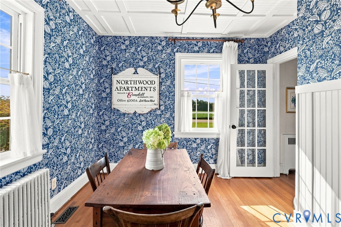 Hardwood flooring, wainscoting, coffered ceiling, French-style door, and window with a white frame