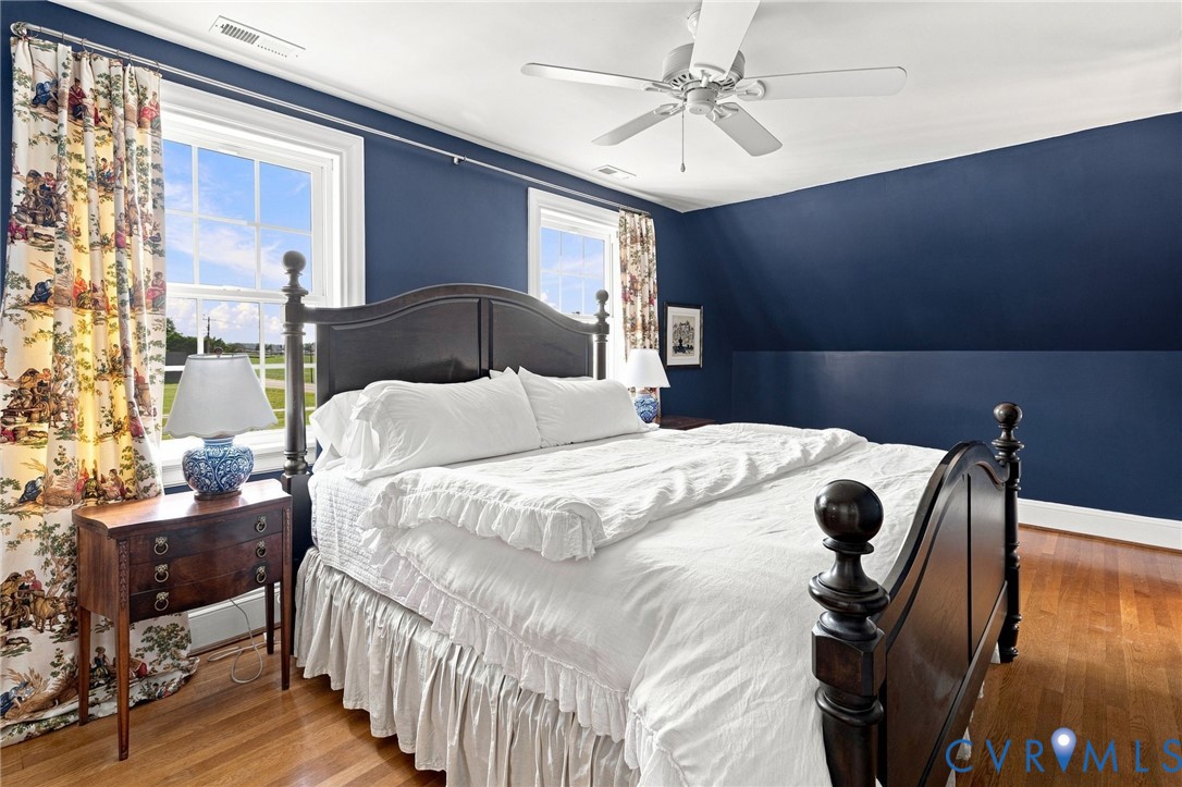 Hardwood flooring, painted walls, two large windows, ceiling fan, and built-in architectural detail