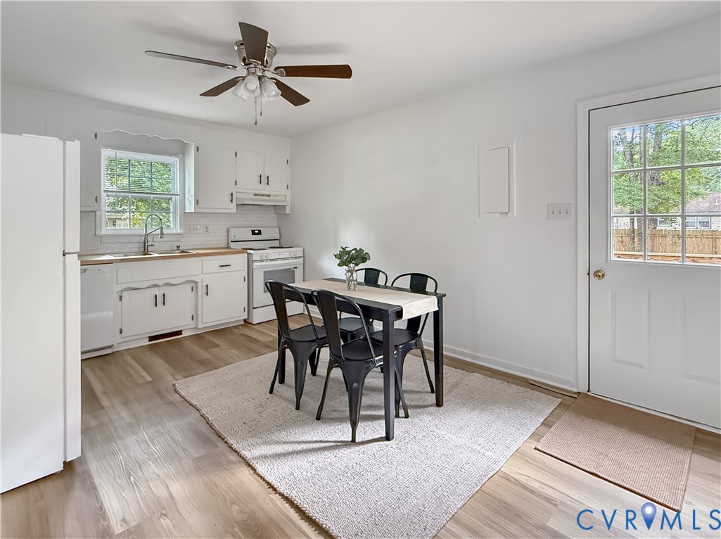 Kitchen featuring white cabinetry, wood-finish flooring, white subway tile backsplash, and a ceiling fan with light fixture Kitchen featuring white cabinetry, wood-finish flooring, white subway tile backsplash, and a ceiling fan with light fixture