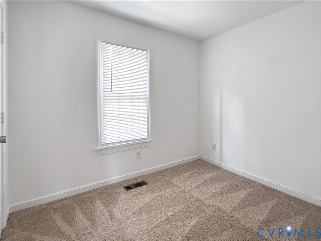 Neutral-toned patterned carpeting, white painted walls, and a window with horizontal blinds