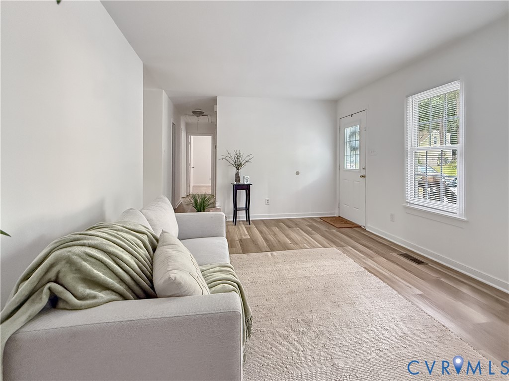 Wood-finish flooring, white walls, white trim, and a white entry door with glass inserts Wood-finish flooring, white walls, white trim, and a white entry door with glass inserts