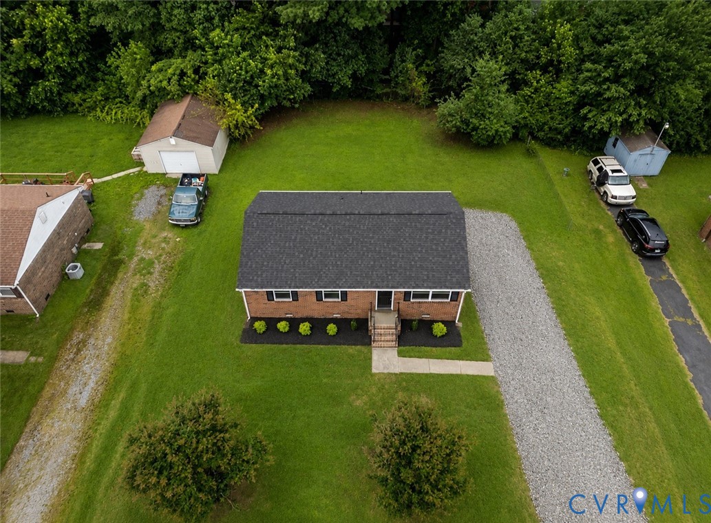Brick exterior residence with a dark shingle roof and a gravel driveway