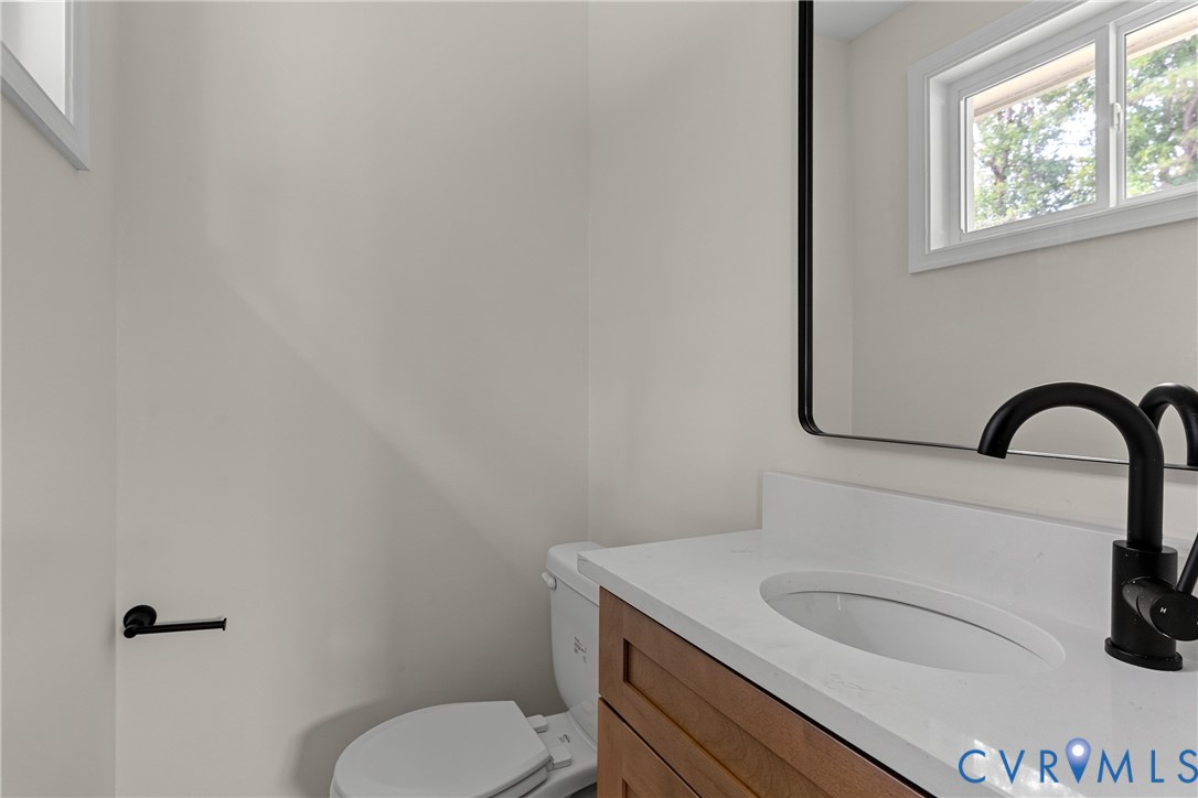 Bathroom vanity featuring a white countertop, oval undermount sink, and matte black faucet