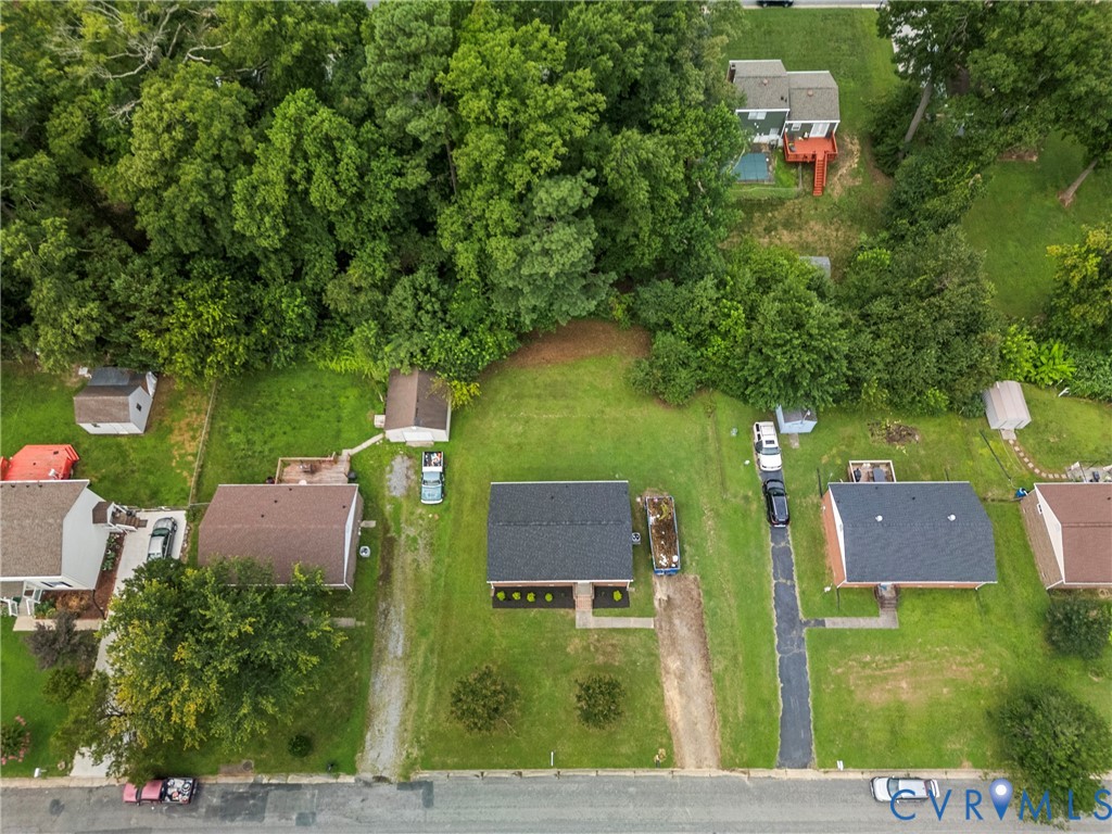 Aerial perspective showcasing a property with a dark shingle roof, surrounded by mature trees