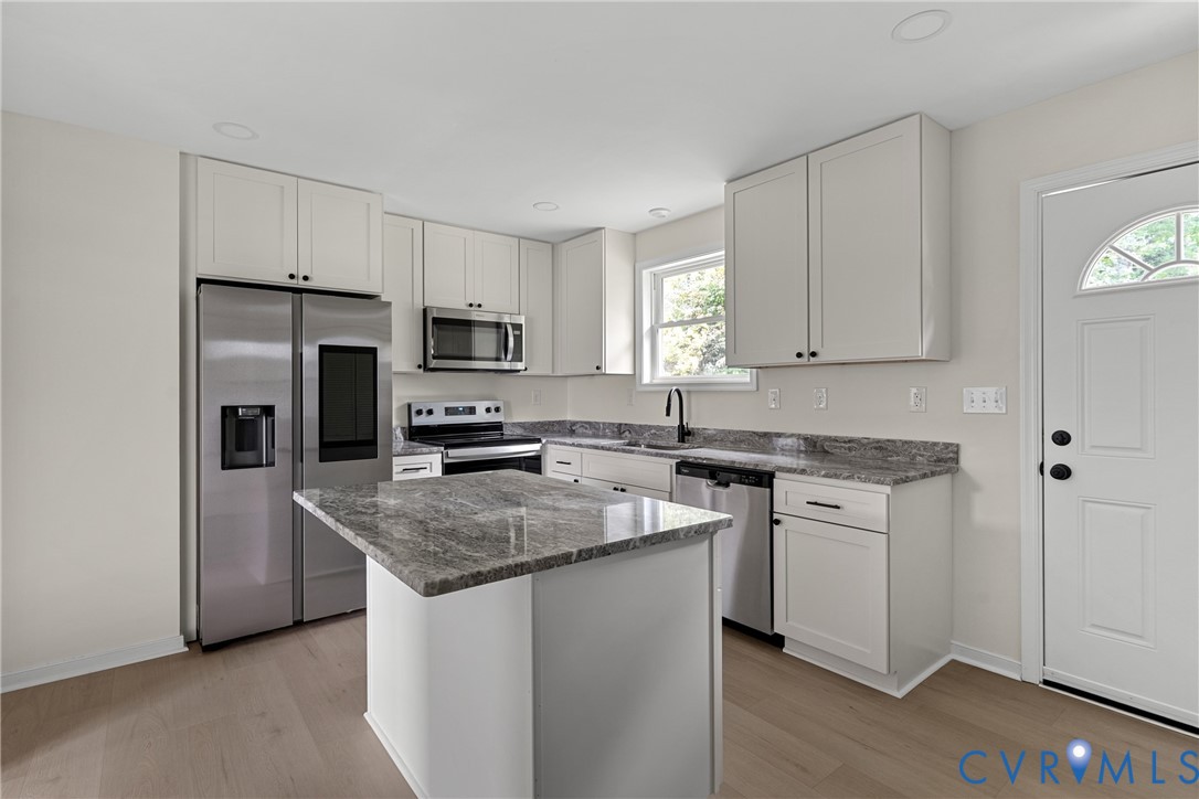 Kitchen featuring light-toned cabinetry, stainless steel appliances, and wood-finish flooring