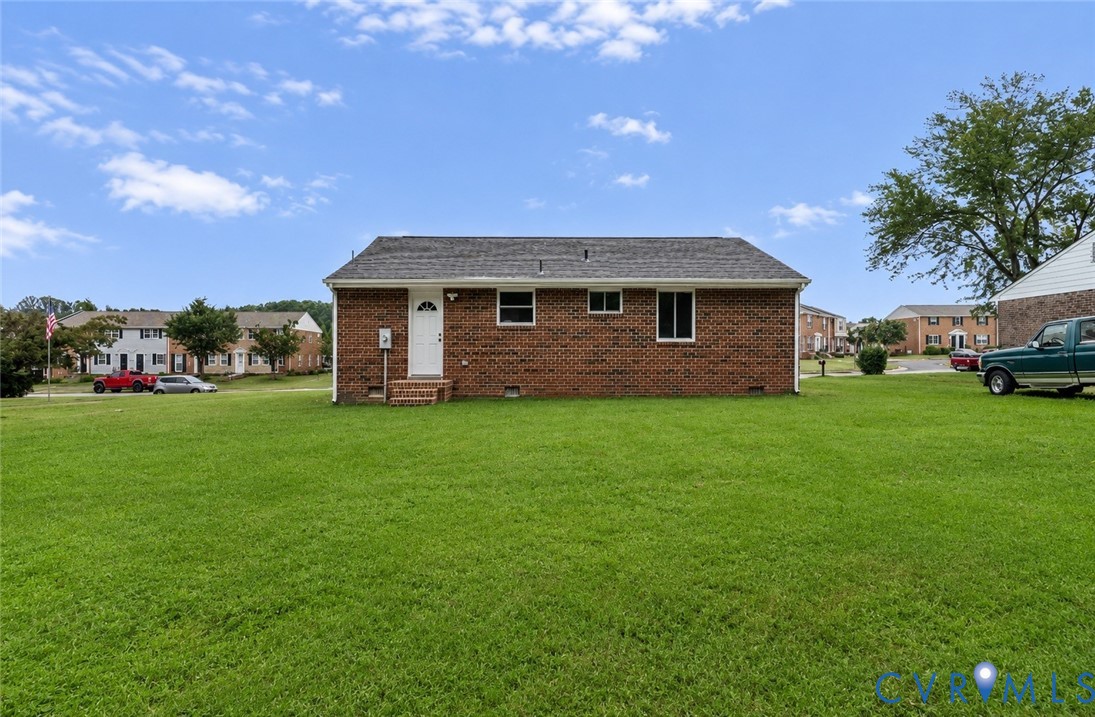 Expansive green lawn surrounds a brick exterior residence with a shingle roof