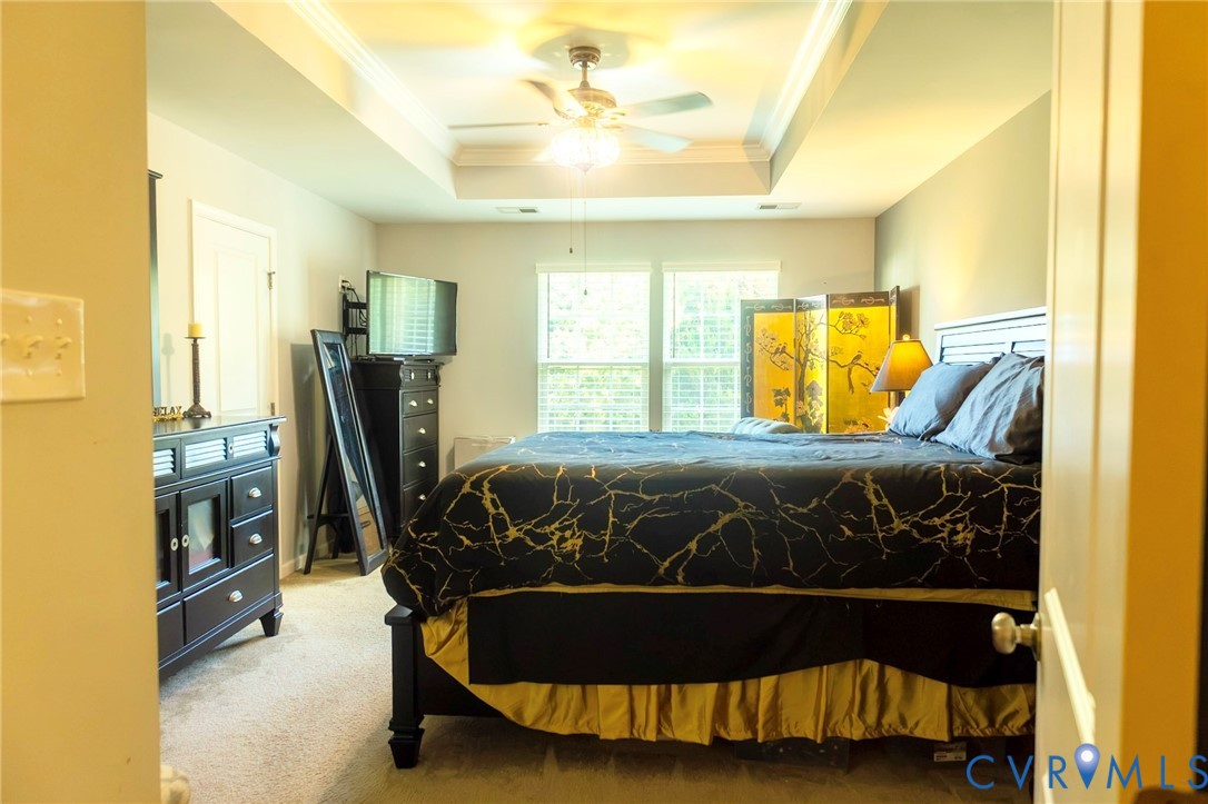 Recessed tray ceiling, ceiling fan with integrated lighting, double windows, and carpeted flooring