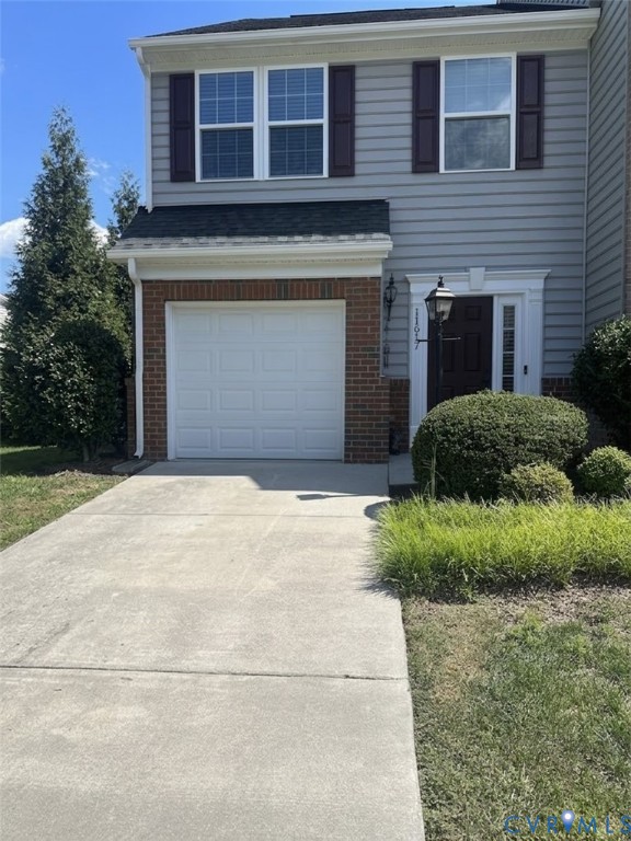 Grey siding exterior with brick accents, white garage door, and a concrete driveway Grey siding exterior with brick accents, white garage door, and a concrete driveway
