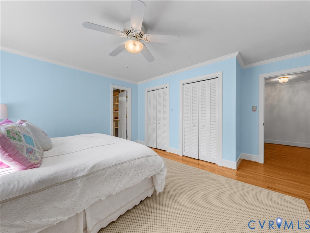Hardwood flooring, painted walls, ceiling fan with integrated lighting, and louvered closet doors