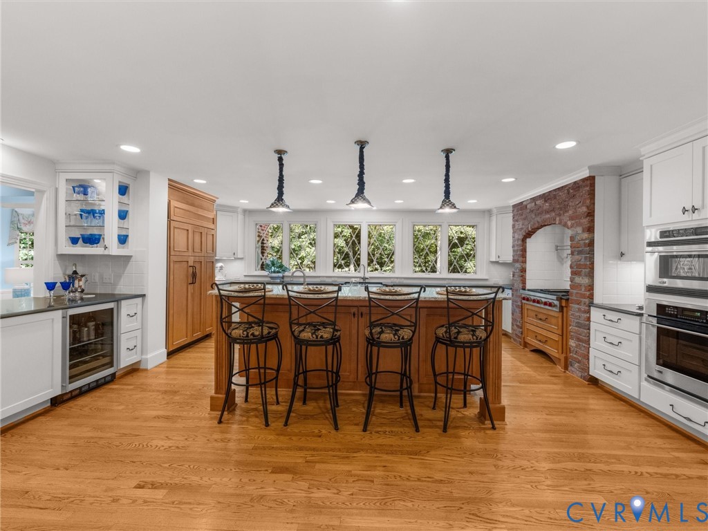 Kitchen featuring a central island, recessed lighting, wood-finish flooring, white cabinetry, and stainless steel appliances