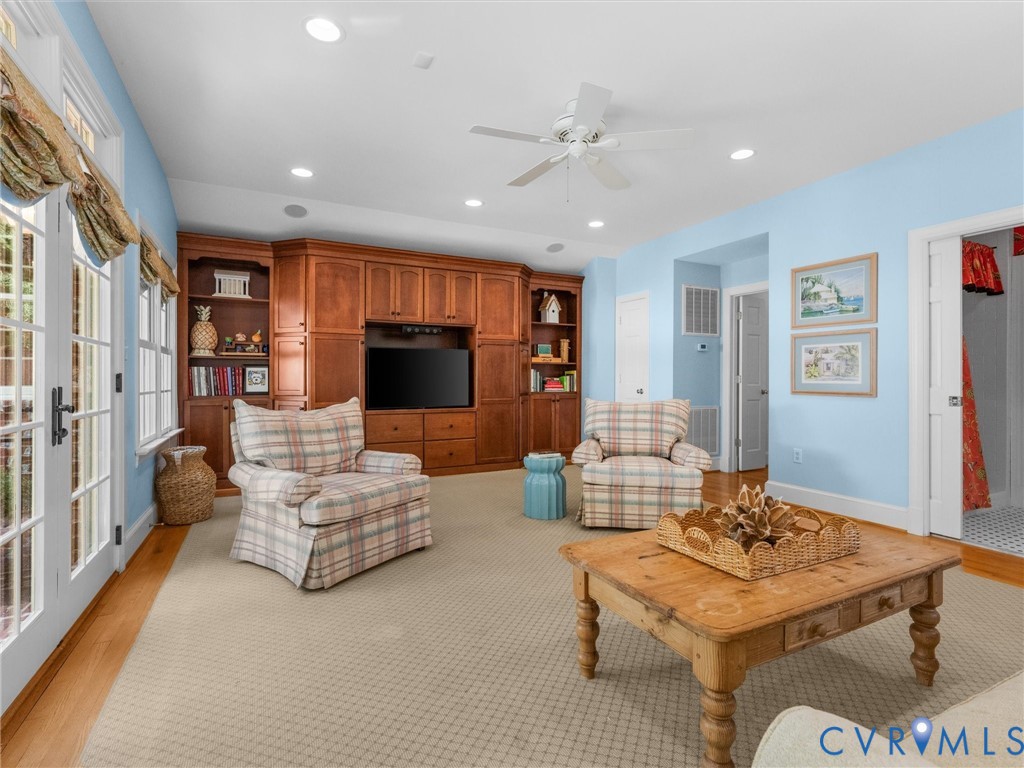 Built-in wood cabinetry with integrated media center, recessed lighting, ceiling fan, carpeted flooring, and French doors with transoms