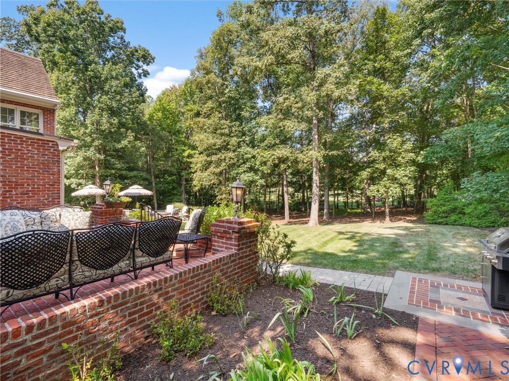 Brick exterior featuring multiple windows, a manicured lawn, and mature trees