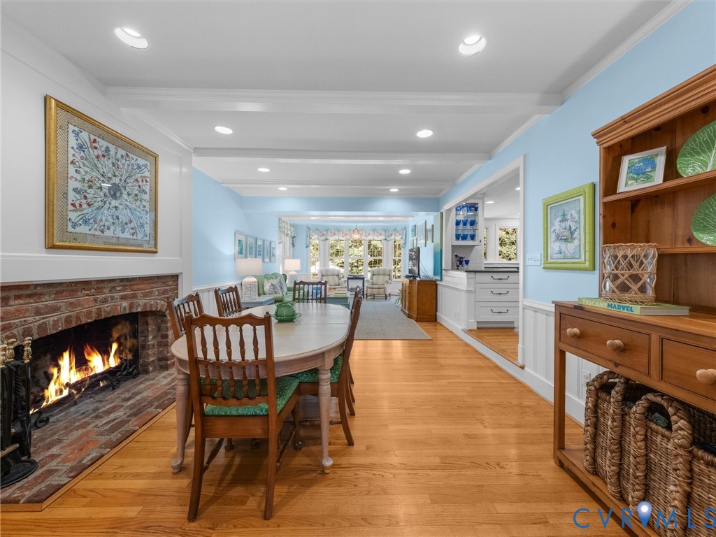 Hardwood flooring throughout, brick fireplace with hearth, recessed lighting, crown molding, and wainscoting