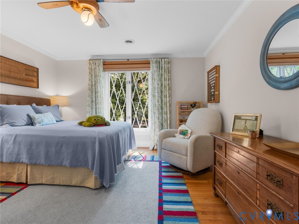 Hardwood flooring, crown molding, ceiling fan, decorative window grilles, and a light-colored wall finish