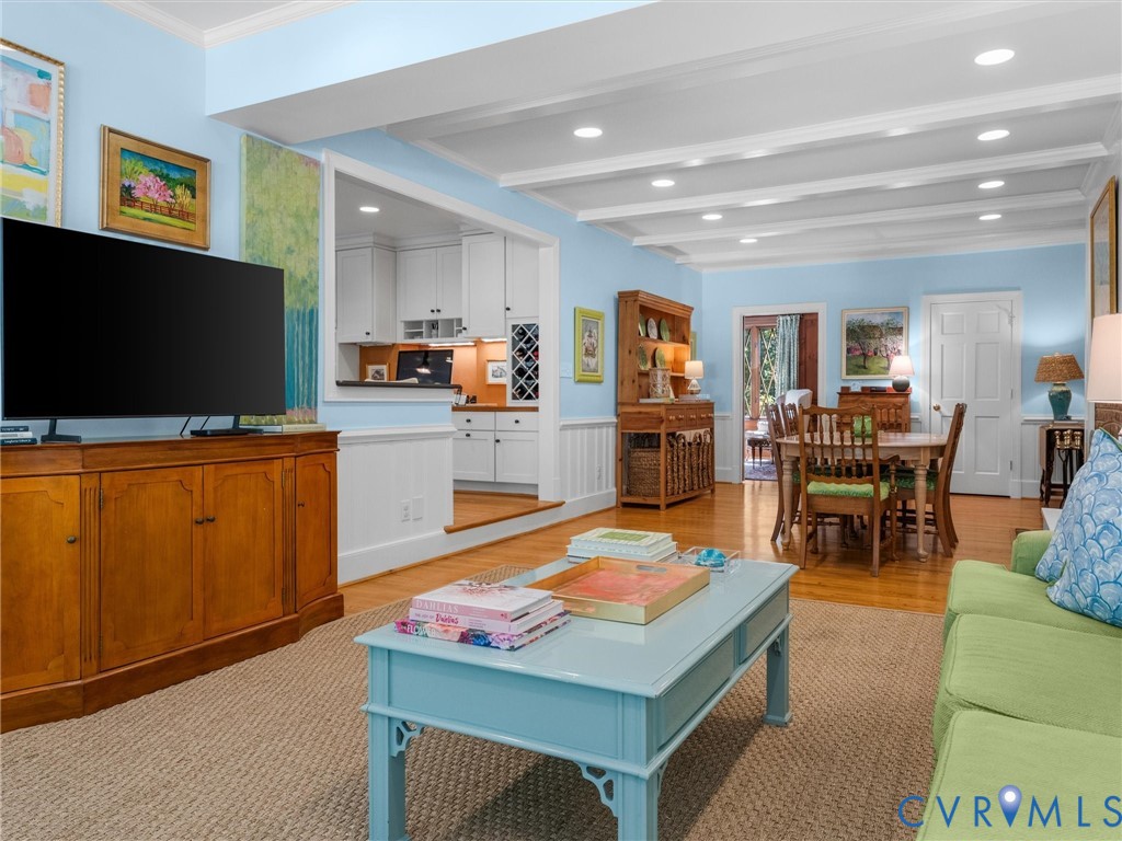 Hardwood flooring, coffered ceiling with recessed lighting, wainscoting, built-in wine rack, and white cabinetry