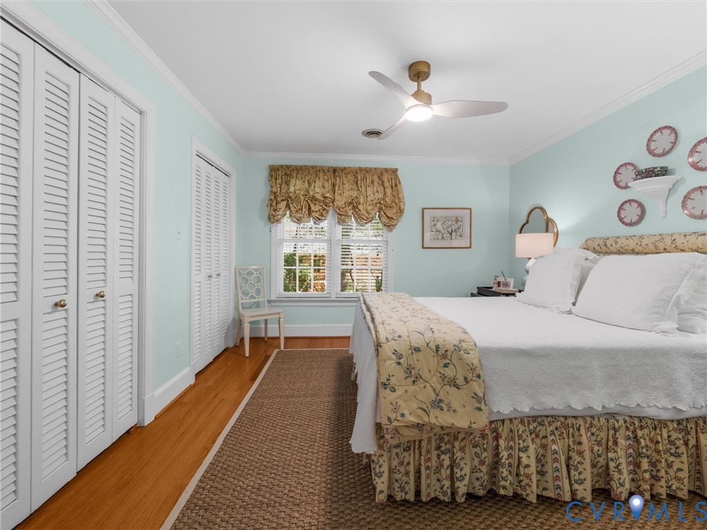 Louvered closet doors, wood-finish flooring, and a ceiling fan with integrated lighting