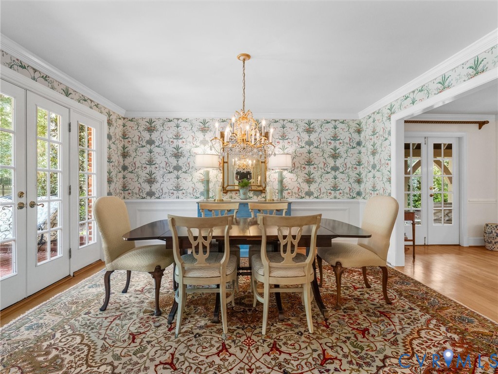 Hardwood flooring, chandelier lighting, decorative wall covering, white trim, and double French doors