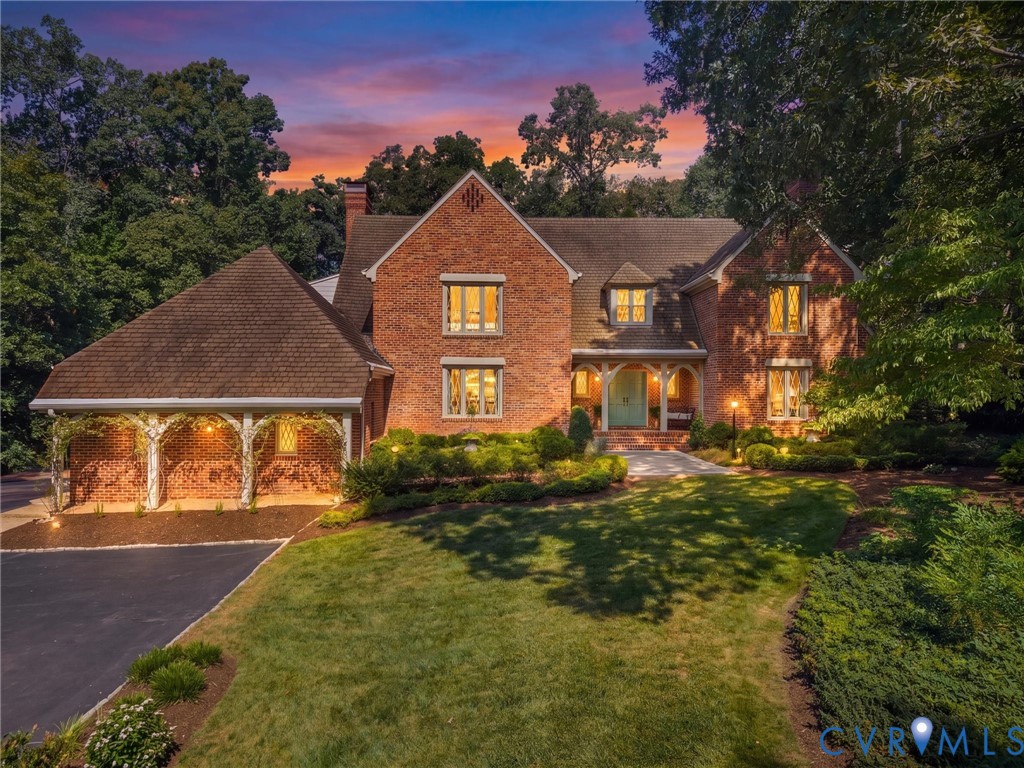 Brick exterior with a prominent front entrance, dormer windows, and an attached carport featuring decorative archways Brick exterior with a prominent front entrance, dormer windows, and an attached carport featuring decorative archways