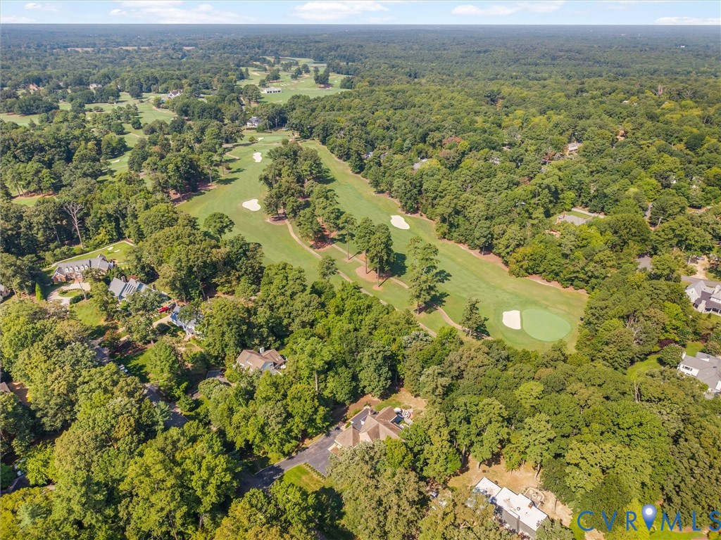 Aerial perspective showcasing surrounding mature trees and a golf course with greens and sand traps