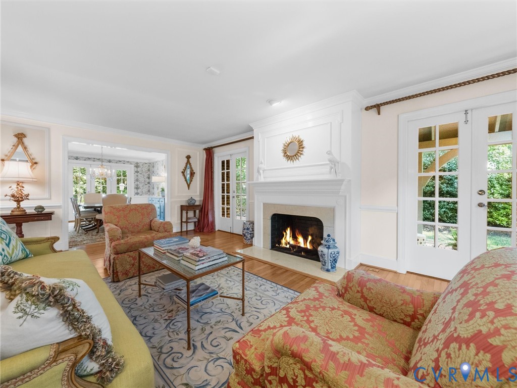 Hardwood flooring, an ornate fireplace with mantel and hearth, and double French doors with transom windows