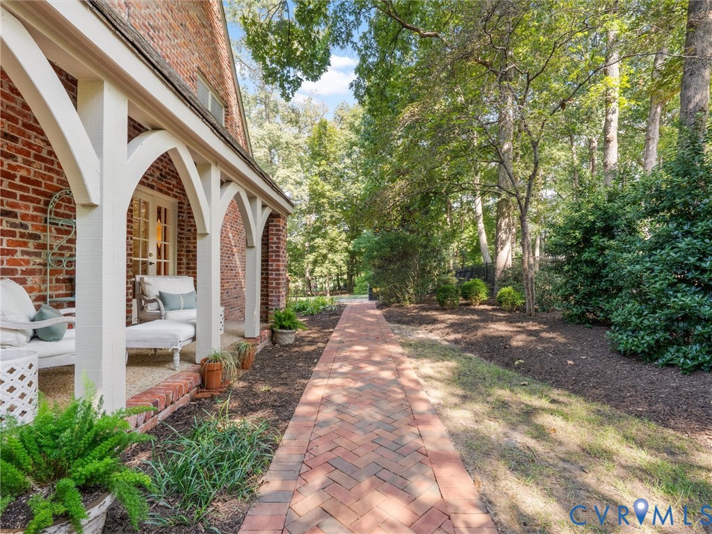 Brick exterior with a covered porch, arched supports, and a herringbone brick pathway