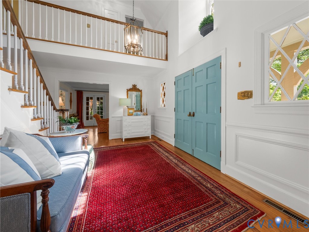 Hardwood flooring, painted paneled doors, white wainscoting, decorative window grilles, and an overhead lighting fixture