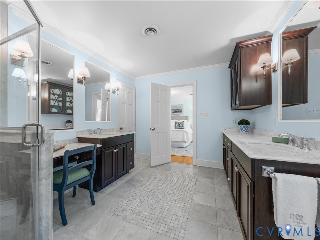Dual dark wood vanities with undermount sinks, stone countertops, and wall-mounted lighting fixtures