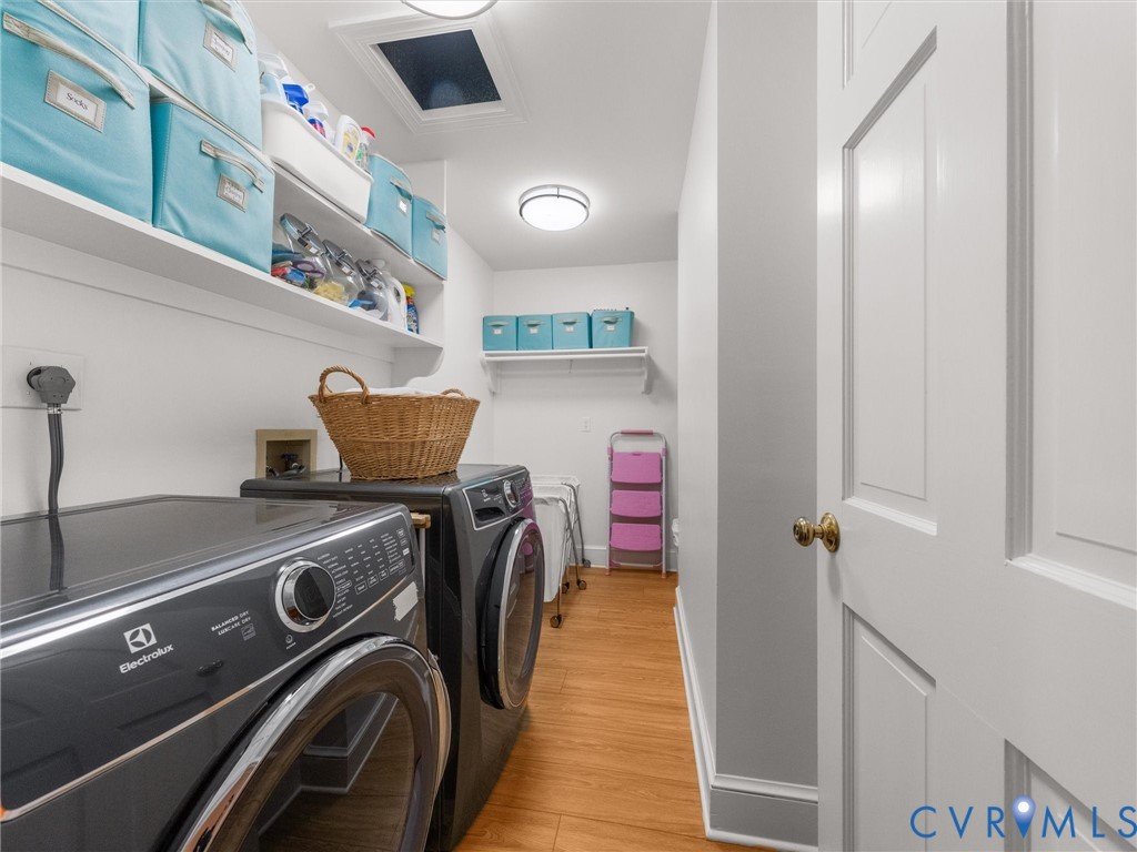 Laundry room with wood-finish flooring, white built-in shelving, and recessed lighting