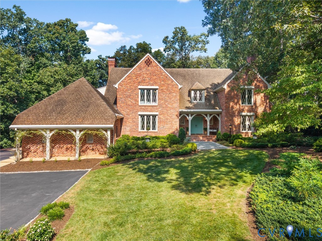 Brick exterior with multiple gables, diamond-pane windows, covered entry porch, asphalt driveway, and mature landscaping Brick exterior with multiple gables, diamond-pane windows, covered entry porch, asphalt driveway, and mature landscaping