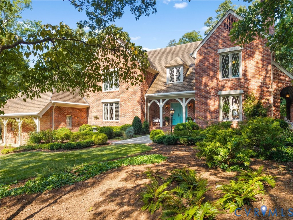 Brick exterior with diamond-patterned windows, a gabled roofline, a covered entry with white columns, and a bright blue double front door Brick exterior with diamond-patterned windows, a gabled roofline, a covered entry with white columns, and a bright blue double front door