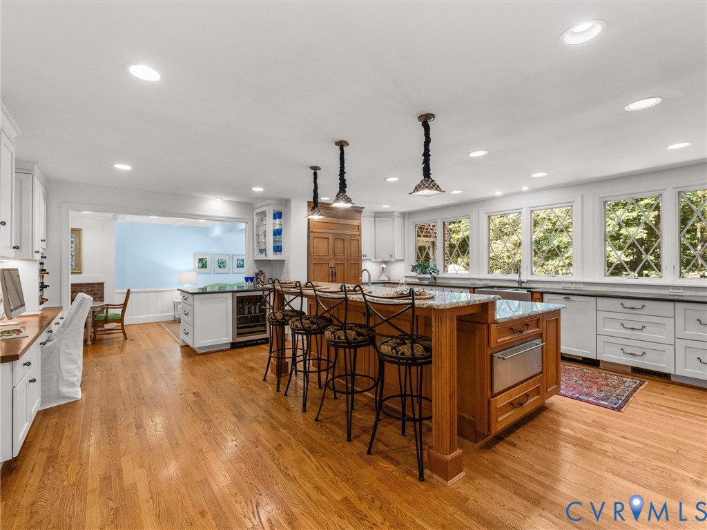 Hardwood flooring throughout the kitchen, complemented by a large center island with integrated appliances and pendant lighting