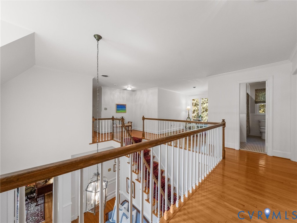 Hardwood flooring, painted white balusters, wooden handrail, and chandelier