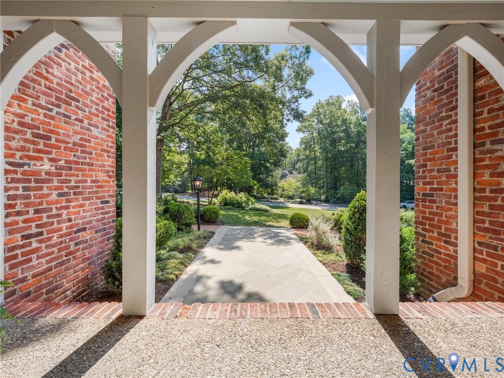 Brick exterior with white archway details, a flagstone pathway, and landscaped grounds featuring mature trees and shrubs Brick exterior with white archway details, a flagstone pathway, and landscaped grounds featuring mature trees and shrubs