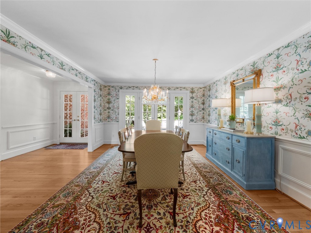 Hardwood flooring, decorative wainscoting, intricate wallpaper, double French doors, and a decorative chandelier