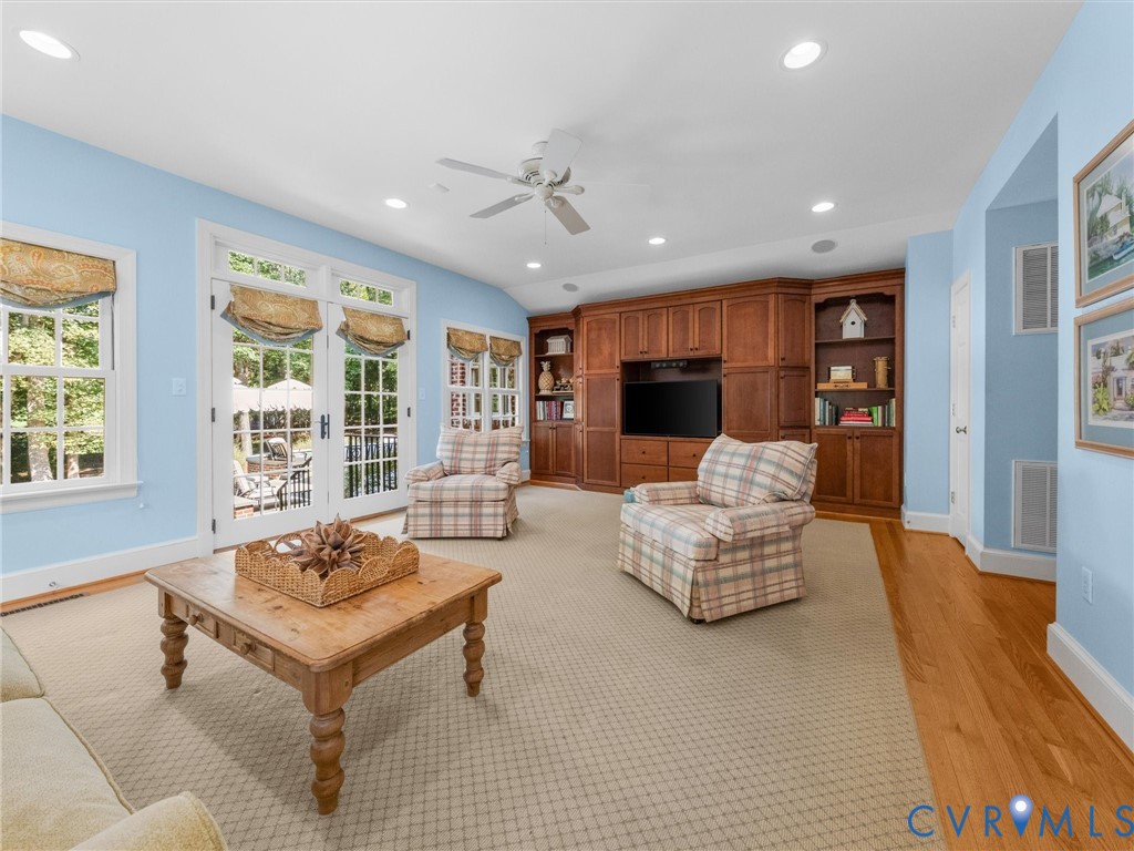 Built-in cabinetry with integrated shelving, recessed lighting, ceiling fan, carpet flooring, and double French doors to the exterior